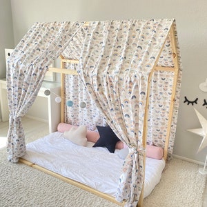 May include: A wooden bed frame with a white canopy featuring a rainbow pattern. The canopy is draped over the bed, creating a cozy and whimsical atmosphere. The bed is made with white bedding and has a few pillows.