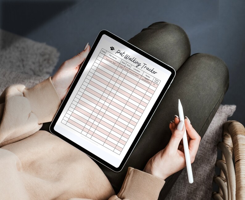 May include: A digital tablet with a white background and a black grid. The tablet is displaying a "Pet Walking Tracker" checklist with columns for date, pet name, start time, end time, location, amount of poop, additional notes, and total time. A white stylus is lying on the tablet.