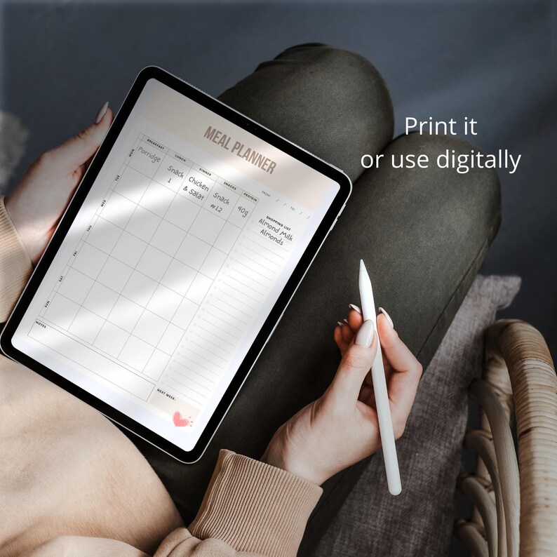 May include: A digital meal planner on a tablet with a white stylus. The planner has columns for breakfast, snack, lunch, snack, dinner, and a shopping list. The text "MEAL PLANNER" is at the top of the planner. The text "Print it or use digitally" is in the upper right corner of the image.