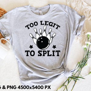 May include: A light gray t-shirt featuring a bowling design with the text "TOO LEGIT TO SPLIT" in black. The graphic includes a bowling ball, pins, and stars. The shirt is folded and tied at the bottom.
