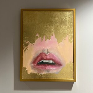 May include: A framed painting of a close-up of a woman's lips with a gold background.