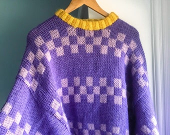 May include: Purple and white checkered knit sweater with a yellow ribbed collar.