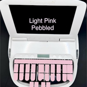 May include: A white Stenograph machine with a light pink pebbled keyboard. The machine has a small screen on the top and a row of keys below the screen.