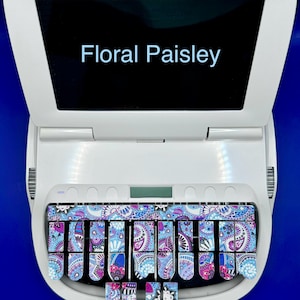 May include: A white Stenograph machine with a black screen that says "Floral Paisley". The keys are covered with a floral paisley design in shades of blue, purple, and pink.