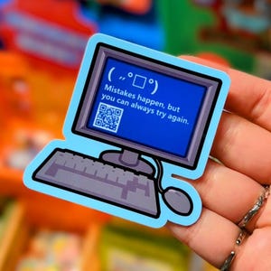 Könnte beinhalten: Ein blauer Computer-förmiger Aufkleber mit einem blauen Bildschirm, der den Text "Mistakes happen, but you can always try again." und einen QR-Code anzeigt. Der Aufkleber hat ein Tastatur- und Maus-Design.