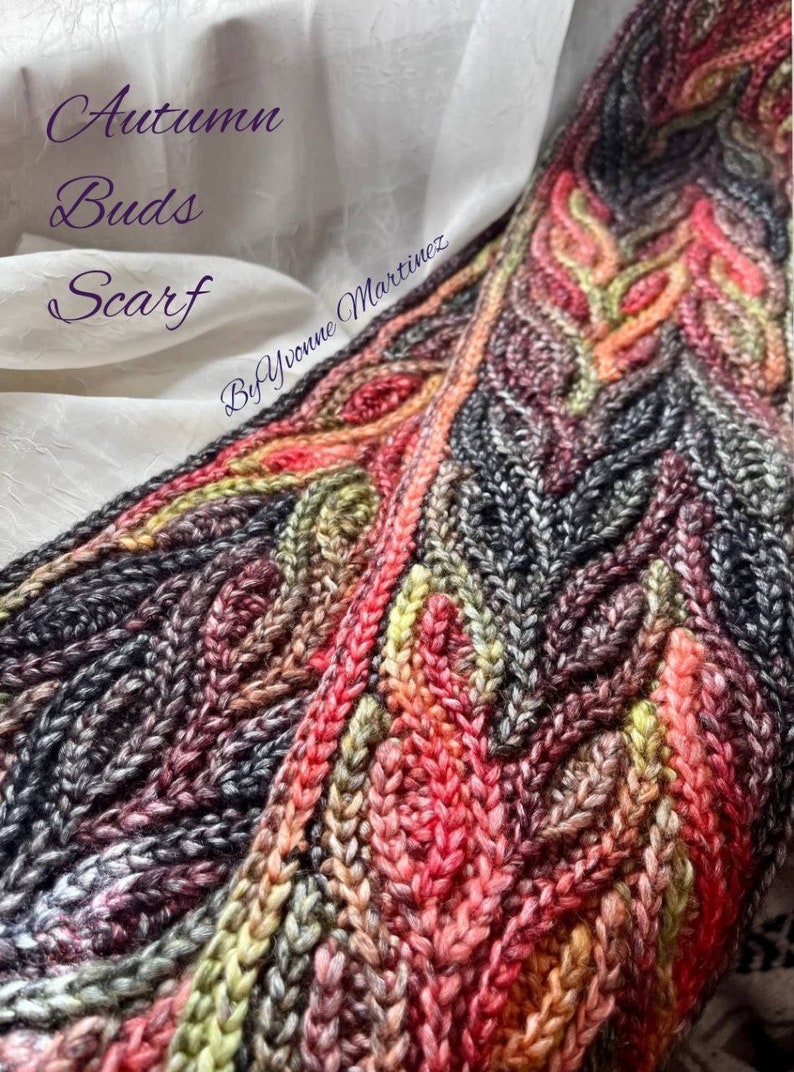 Puede incluir: Una bufanda de ganchillo colorida con un patr&oacute;n texturizado. La bufanda est&aacute; hecha con una variedad de tonos de hilo rojo, naranja, amarillo, verde y gris. El texto "Autumn Buds Scarf by Yvonne Martinez" est&aacute; escrito en la bufanda.