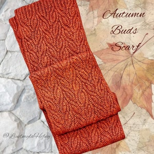 Puede incluir: Un primer plano de una bufanda de punto de color naranja quemado. La bufanda tiene un patr&oacute;n de punto de cable y est&aacute; doblada por la mitad. El texto "Autumn Buds Scarf" es visible en la imagen.