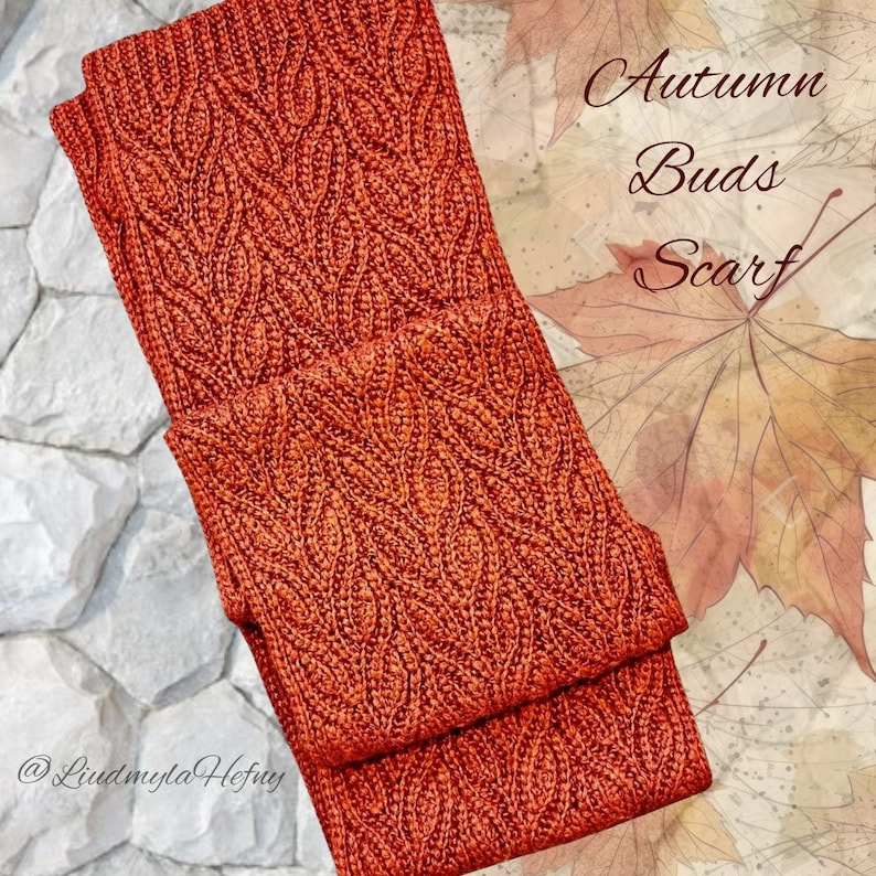Puede incluir: Un primer plano de una bufanda de punto de color naranja quemado. La bufanda tiene un patr&oacute;n de punto de cable y est&aacute; doblada por la mitad. El texto "Autumn Buds Scarf" es visible en la imagen.