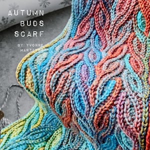 Puede incluir: Una bufanda de punto colorida con un patr&oacute;n de trenza. La bufanda est&aacute; hecha con un hilo degradado que pasa del azul al naranja al amarillo. La bufanda se titula "Autumn Buds Scarf" por Yvonne Martinez.