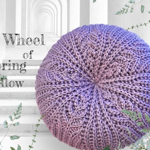 May include: A purple and pink crocheted cushion with a wheel-like design. The cushion is called "Wheel of Spring Pillow".