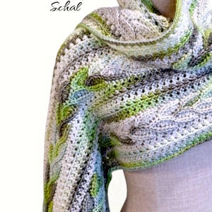 May include: A crocheted shawl in shades of gray, white, and green, with a textured cable knit design. The text "Silver Birch Schal" is at the top, and "MajesticArtCrochet" is at the bottom.