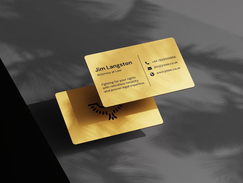 May include: Two gold business cards with rounded corners. The top card displays contact information for Jim Langston, Attorney at Law, including a phone number, email, and website. The bottom card shows a logo. The cards are on a dark grey surface.