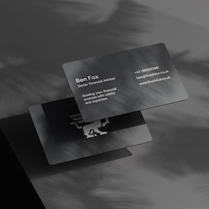 May include: Two dark grey business cards with rounded corners. The top card displays the name "Ben Fox, Senior Financial Advisor" and contact details. The bottom card features a logo. The cards are slightly overlapping, with shadows.