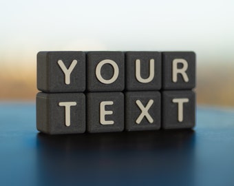 May include: Black letter blocks spelling out the words "YOUR TEXT" on a blue surface.