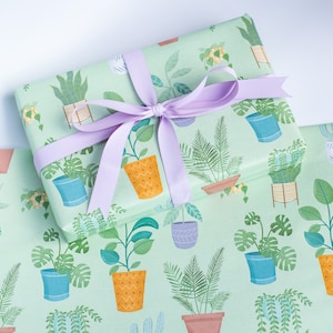 May include: Green gift wrap with a pattern of potted plants. The wrap is tied with a lavender ribbon.