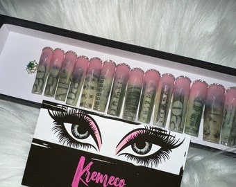May include: A set of pink and white artificial nails with a money design. The nails are in a black box with a business card that says "Kremico Artificial Nails".