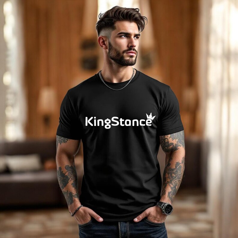 Puede incluir: Camiseta negra con el texto blanco "KingStance" y un dise&ntilde;o de corona. La camiseta de manga corta est&aacute; hecha de un material suave.