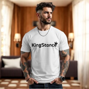 Puede incluir: Camiseta blanca de cuello redondo con el texto "KingStance" en negro y un gr&aacute;fico de corona. La persona que lleva la camiseta tiene tatuajes en los brazos y un collar de cadena plateada.