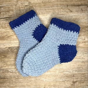 May include: A pair of cosy blue and grey fuzzy socks. The socks have a contrasting colour block design.