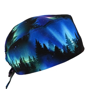 May include: A blue and black scrub cap featuring a starry night sky and silhouette of a forest. The cap has a tie in the back for an adjustable fit. The fabric is printed with a gradient of blues and greens.