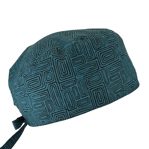 May include: Teal and black patterned scrub cap. The cap features a repeating geometric design in black on a teal background. The cap has a tie in the back for an adjustable fit. The cap is made of a soft, breathable fabric.