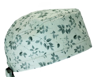 Pode incluir: Um gorro cirúrgico verde claro com um padrão de folhas. O gorro tem um laço na parte de trás.