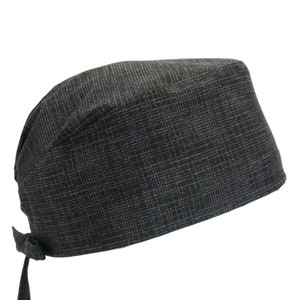 May include: A black scrub cap with a subtle textured pattern. The cap has a tie at the back.