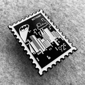 May include: Black and white enamel pin featuring a stylized cityscape with the Batman logo and the text "Gotham" and "92&cent;".