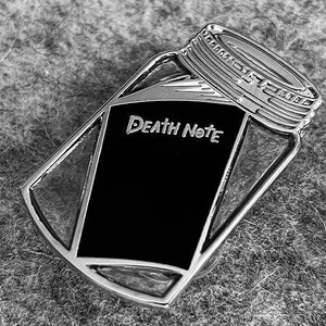 May include: A silver metal pin shaped like a mason jar with the words "Death Note" on the front.