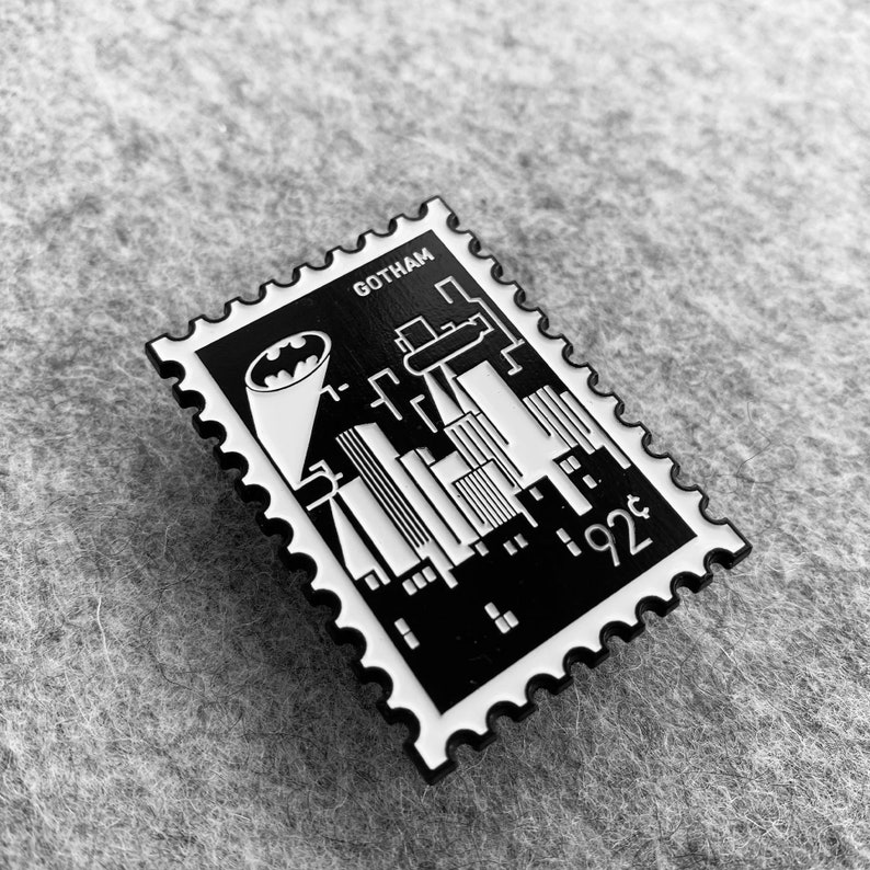 May include: Black and white enamel pin featuring a stylized cityscape with the Batman logo and the text "Gotham" and "92&cent;".