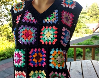 Può includere: Un gilet di uncinetto nero con scollo a V e un motivo a quadrati della nonna colorati.
