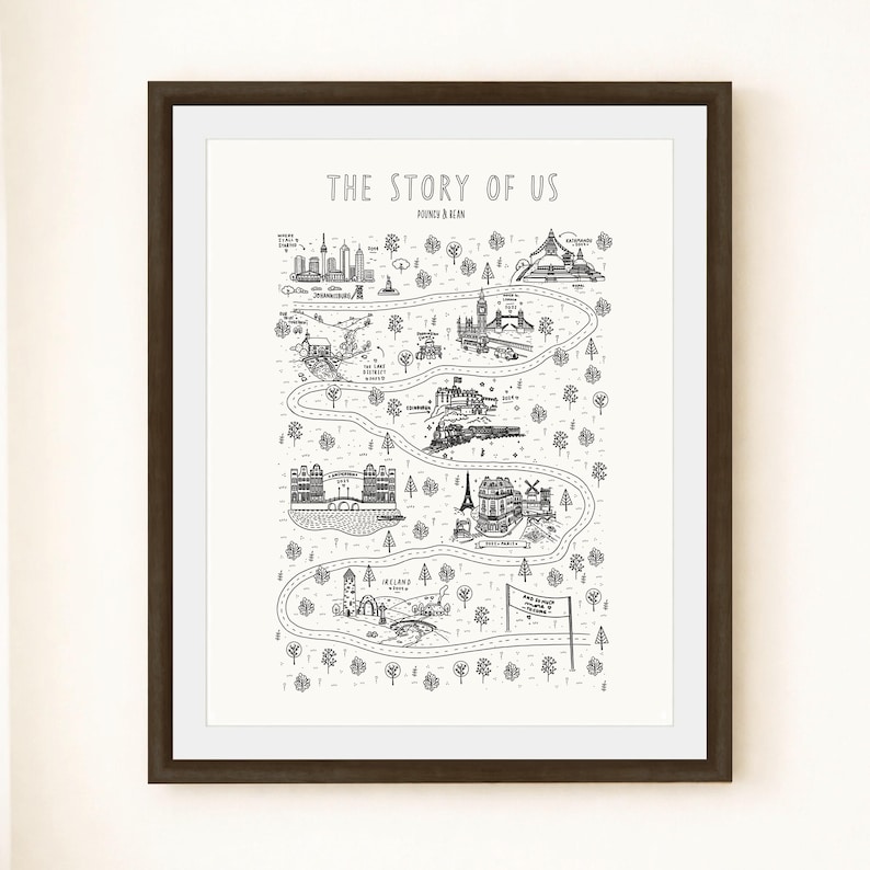 K&ouml;nnte beinhalten: Ein gerahmter schwarz-wei&szlig;er Druck mit dem Titel THE STORY OF US, der eine gewundene Stra&szlig;enkartenillustration mit verschiedenen Sehensw&uuml;rdigkeiten, B&auml;umen und Textbeschriftungen zeigt. Das Kunstwerk ist in einem dunkelbraunen Rahmen mit wei&szlig;em Passepartout.