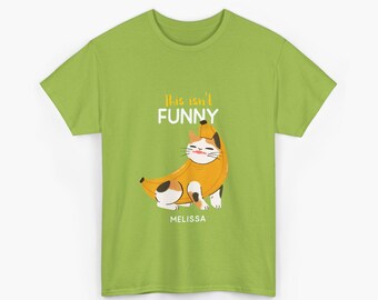 May include: Lime green t-shirt with a cartoon cat in a banana costume. The cat has a white face with brown and black markings. Text above the cat reads "This isn't FUNNY" and the name "MELISSA" is below the cat.