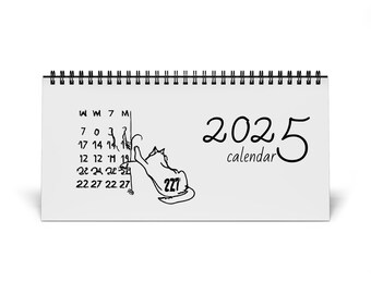 Puede incluir: Un calendario de escritorio blanco con una ilustración en blanco y negro de un gato arañando un calendario. El calendario es para el año 2025.