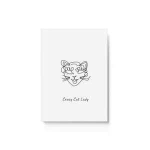 May include: A white notebook with a black line drawing of a cat's face and the text "Crazy Cat Lady".