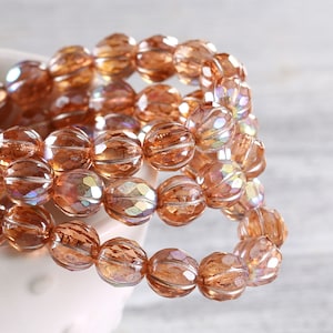 May include: A strand of iridescent brown glass beads with a faceted, textured design. The beads are strung together to form a necklace or bracelet.