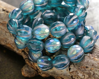 May include: A strand of teal blue glass beads with silver accents. The beads are faceted and have a slightly iridescent finish.