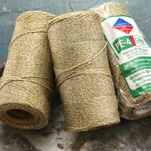 May include: Three spools of gold and silver thread, each with a label that reads "Linhasita Alta Qualidade PE-4 Cera". The label also includes the text "Fio de Poliester Encerado" and "Feito no Brasil".