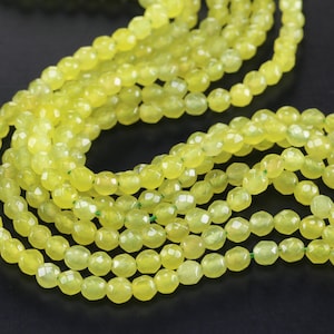 May include: A strand of light green faceted gemstone beads. The beads are round and have a smooth, polished finish.