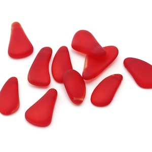 May include: A collection of ten red glass sea glass pieces, each with a unique shape and texture. The sea glass is smooth and polished, with a slightly translucent appearance.