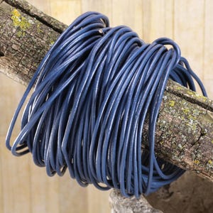 May include: A coil of dark blue leather cord, approximately 1.5 mm thick, wrapped around a piece of weathered wood.