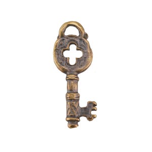 May include: A vintage-style key with a bronze finish. The key features a decorative head with a cross-shaped cutout and ornate detailing on the stem and teeth. The key is likely made of metal and has a slightly aged appearance.