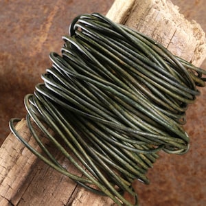 May include: A spool of dark green leather cord, wrapped around a piece of weathered wood.