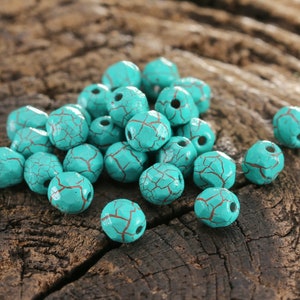 May include: A collection of turquoise blue beads with a cracked finish. The beads are made of wood and have a natural, rustic look.
