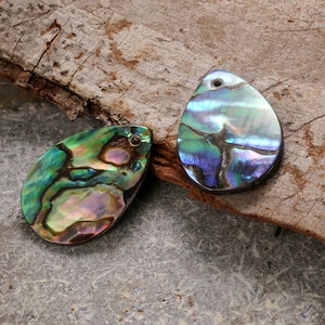 May include: Two iridescent abalone shell pendants with a pearlescent finish. The shells are green, blue, and purple with a natural, organic pattern.