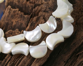 May include: A strand of white mother of pearl crescent moon shaped beads. The beads are strung together on a clear thread.