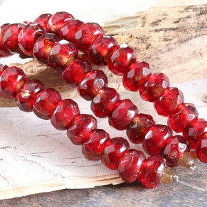 May include: A strand of red glass beads with a faceted finish. The beads have a gold fleck throughout.