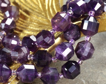 May include: A strand of faceted amethyst beads, each bead is a deep purple color and has a faceted, geometric shape. The beads are strung on a silver thread and are arranged in a loose, flowing pattern.