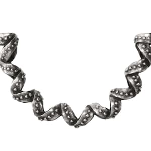 May include: A silver-toned, decorative candle holder with a unique, wavy design. The holder features two circular cups at each end, connected by a twisted, ribbon-like structure. Small, round embellishments dot the surface.