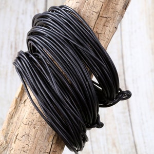 May include: A spool of black leather cord, wrapped around a piece of driftwood.